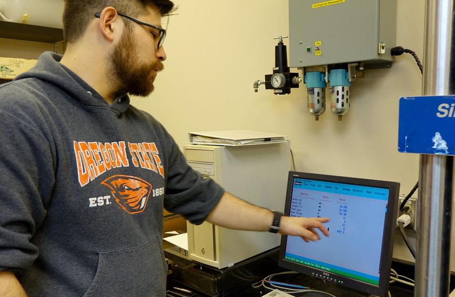 OSU researcher Byrne Miyamoto monitors how much weight a piece of Western Juniper can hold.